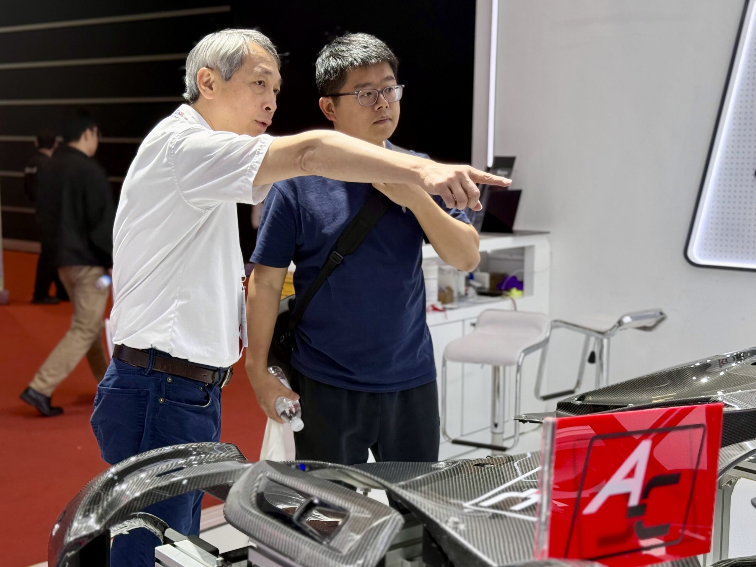 2025年上海车展，艾可迅集团董事长廖国兴（图左）为展台访客解说碳纤维产品。